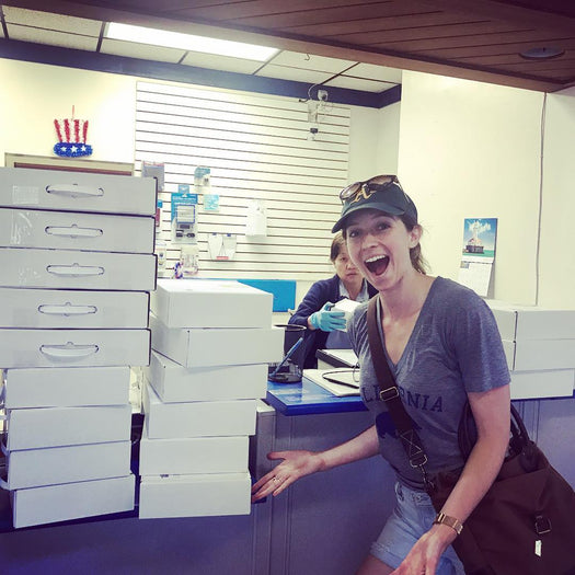 Britt beside stacks of Little Feminist boxes