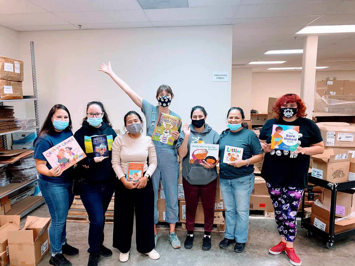 The Little Feminist team holding children’s books in the warehouse