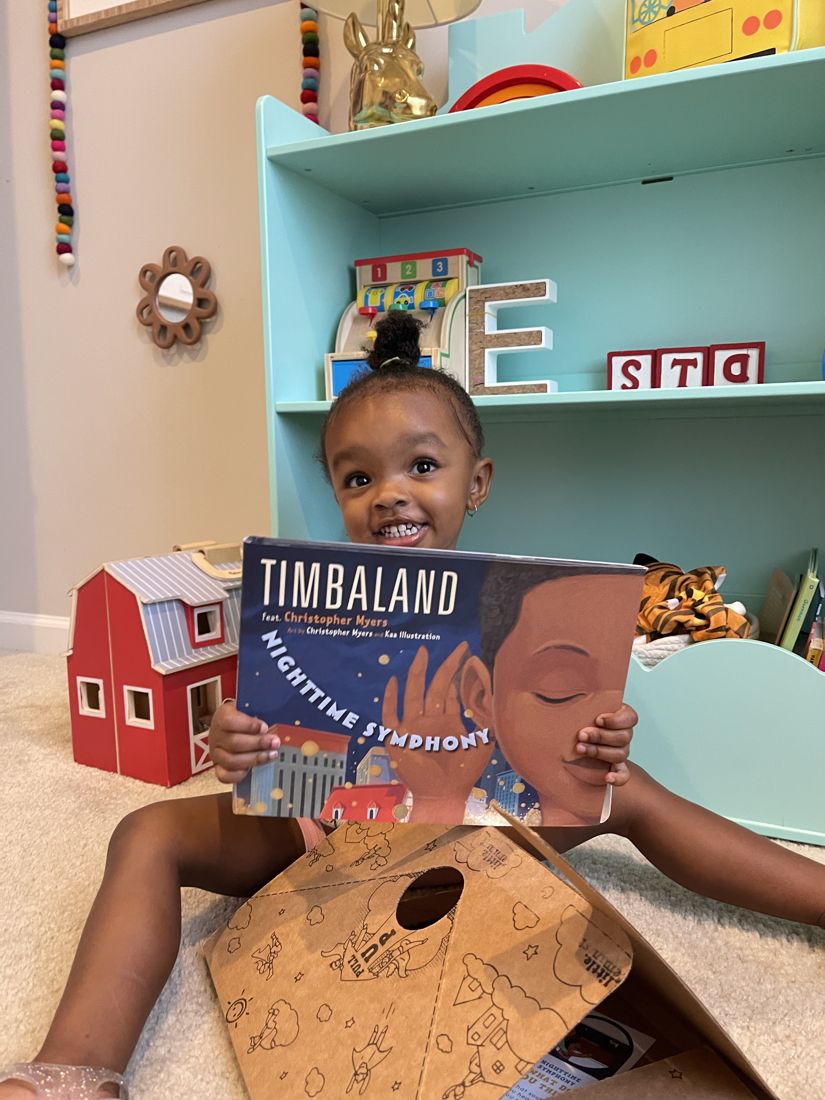 A toddler grinning behind a picture book