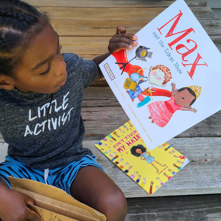 A child holding Max and the Talent Show beside another picture book.