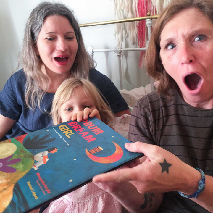 Two adults and a child sharing Drum Dream Girl.